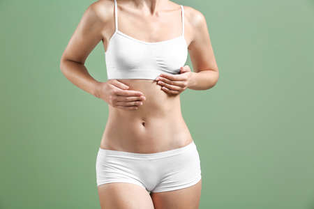 Young woman in underwear on color background. Concept of breast augmentationの写真素材