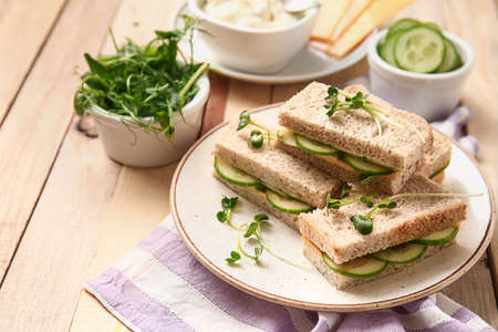 Plate with tasty cucumber sandwiches on wooden tableの写真素材