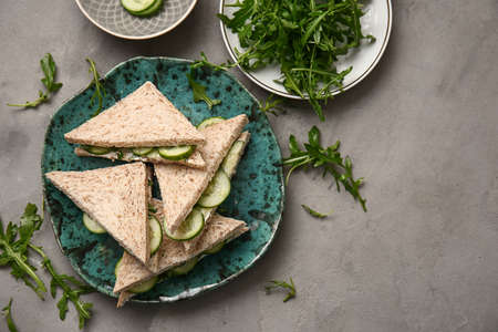 Plate with tasty cucumber sandwiches on gray backgroundの写真素材