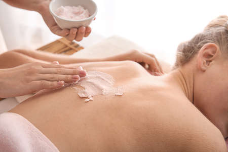 Young woman undergoing treatment with body scrub in spa salonの写真素材
