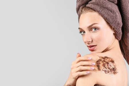 Young woman with body scrub on her body against gray background