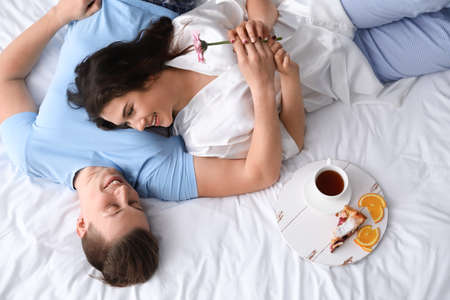 Cute young couple having breakfast in bedの写真素材
