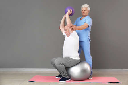 Mature physiotherapist working with senior man in clinic