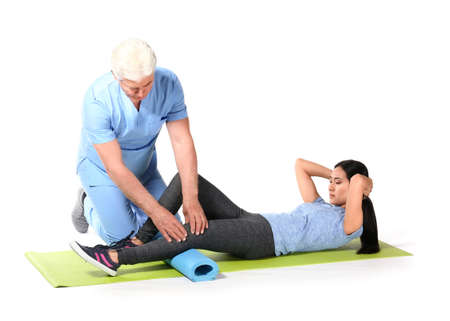 Mature physiotherapist working with young Asian woman on white background