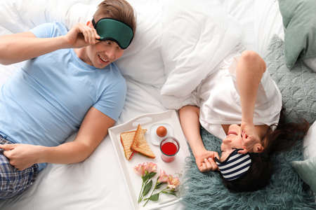 Cute young couple having breakfast in bedの写真素材