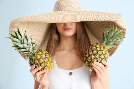 Beautiful young woman with pineapples on white background