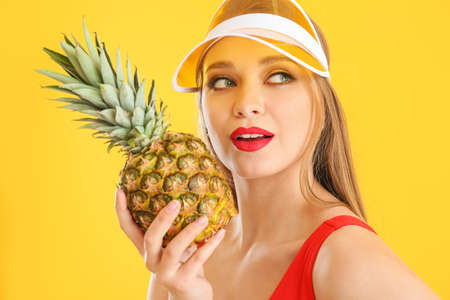 Beautiful young woman with pineapple on color backgroundの写真素材