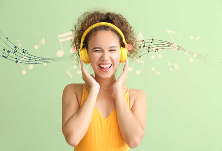 Beautiful young woman listening to music against color background