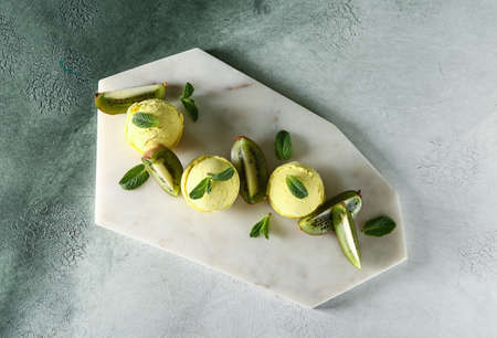 Board with tasty kiwi ice cream on table