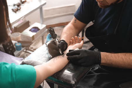 Professional artist making tattoo in salon