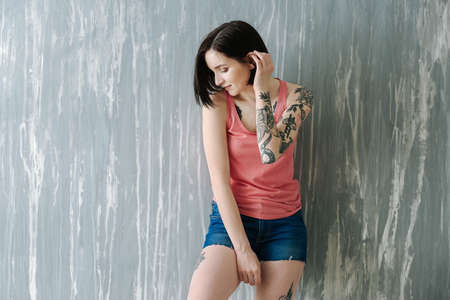 Beautiful tattooed woman near grunge wallの写真素材