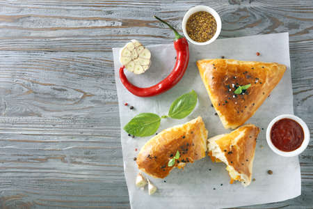 Tasty samosas with sauces on wooden table