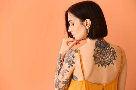 Beautiful tattooed woman on color backgroundの写真素材