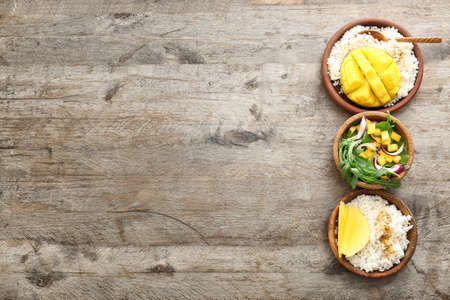 Tasty salad and rice with mango on wooden tableの写真素材