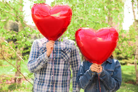 Happy young couple with heart shaped air balloons outdoorsの写真素材