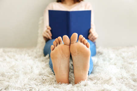 Beautiful young woman reading book at homeの写真素材
