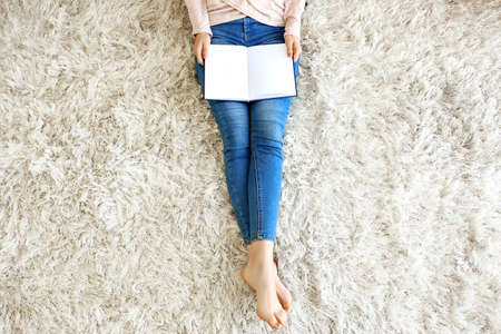 Beautiful young woman reading book at home, top viewの写真素材