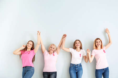 Happy women of different ages with pink ribbons on light background. Breast cancer conceptの写真素材
