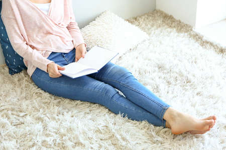 Beautiful young woman reading book at homeの写真素材