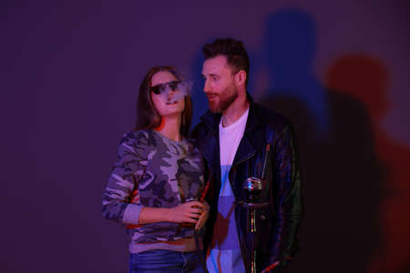 Young couple smoking hookah on dark background