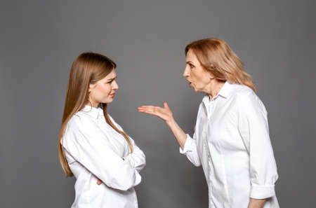 Quarreling mother and daughter on gray background