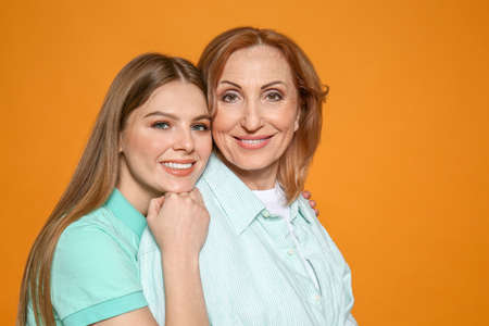 Portrait of happy mother with her daughter on color backgroundの写真素材