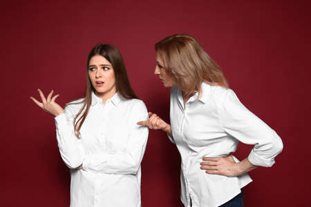Mother scolding her daughter on color backgroundの写真素材