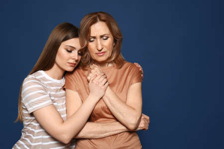 Young woman calming her mother on color backgroundの写真素材