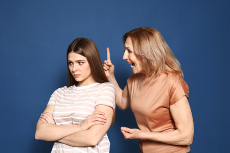 Mother scolding her daughter on color backgroundの写真素材