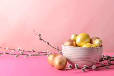 Bowl with beautiful Easter eggs on color tableの写真素材