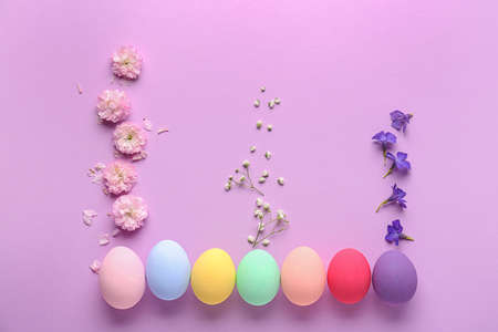 Beautiful Easter eggs with flowers on color backgroundの写真素材