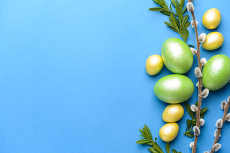 Beautiful Easter eggs and pussy willow on color background