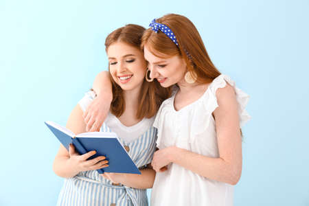 Portrait of beautiful young women with book on color background