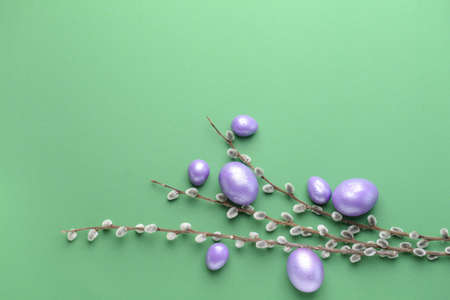 Beautiful Easter eggs and pussy willow on color background