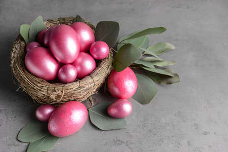 Nest with beautiful Easter eggs on gray background