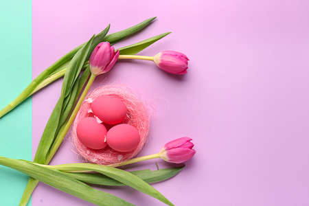 Beautiful Easter eggs with flowers on color backgroundの写真素材
