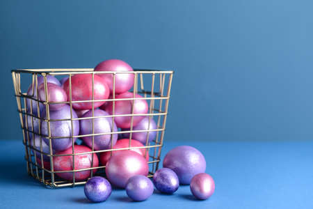 Box with beautiful Easter eggs on color backgroundの写真素材
