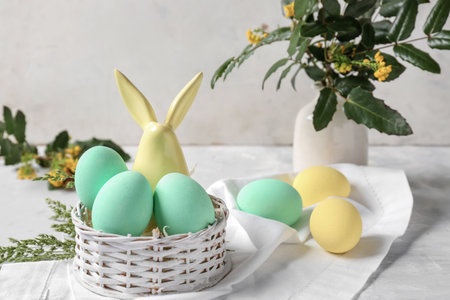 Basket with beautiful Easter eggs on white table
