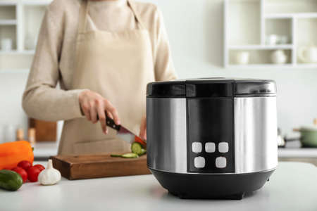 Woman cooking food in multi cooker at home