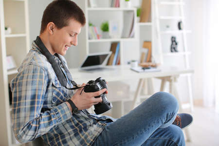 Teenage boy with photo camera at home