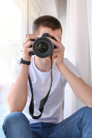 Teenage boy with photo camera near window