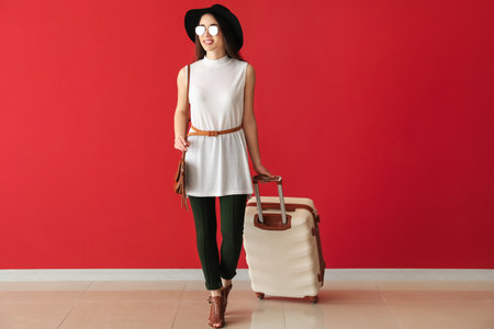 Going young woman with suitcase near color wallの写真素材