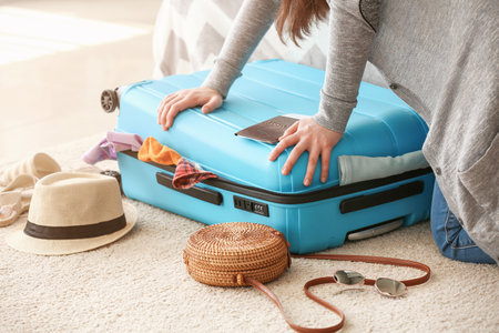 Woman trying to close suitcase with a lot of things. Travel conceptの写真素材