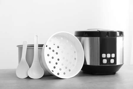 Modern multi cooker on table against light background