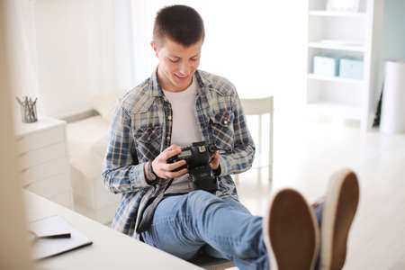 Teenage boy with photo camera at homeの写真素材