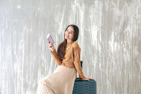 Happy young woman with suitcase, passport and ticket near gray wallの写真素材