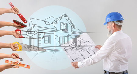Mature male architect with building drawing and many hands with construction tools on gray backgroundの写真素材