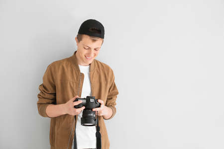 Teenage boy with photo camera on light background
