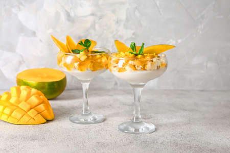 Glasses with tasty mango dessert on gray tableの写真素材