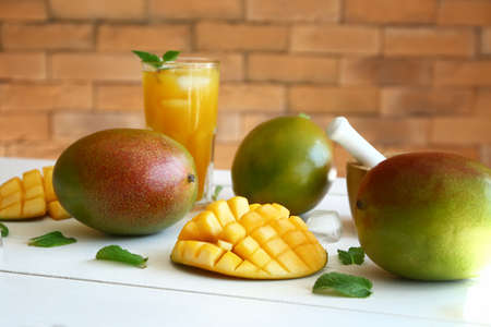 Tasty sweet mango with glass of juice on white table